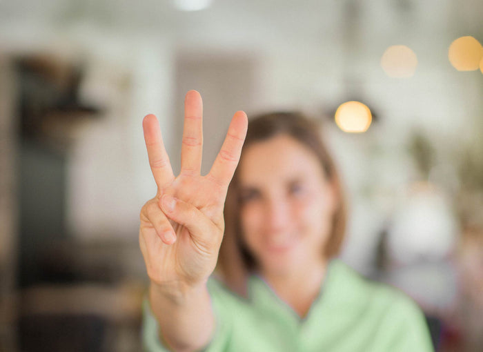 Frau zeigt drei Finger – Symbolbild für drei Ernährungs-Irrtümer im Januar