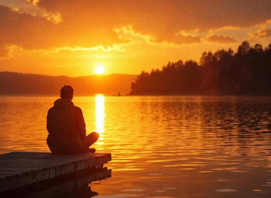 Person sitzt bei Sonnenuntergang an einem See – Symbolbild für Vitamin D3 und K2