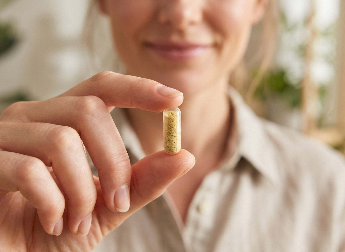 Frau hält eine Kapsel mit gelblichem Pulver in der Hand – Zink-Nahrungsergänzung