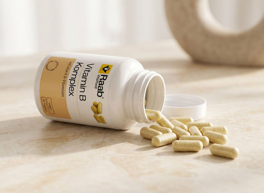 Raab Vitalfood Vitamin B Komplex Kapseln, die aus der Dose auf eine Marmorfläche fallen