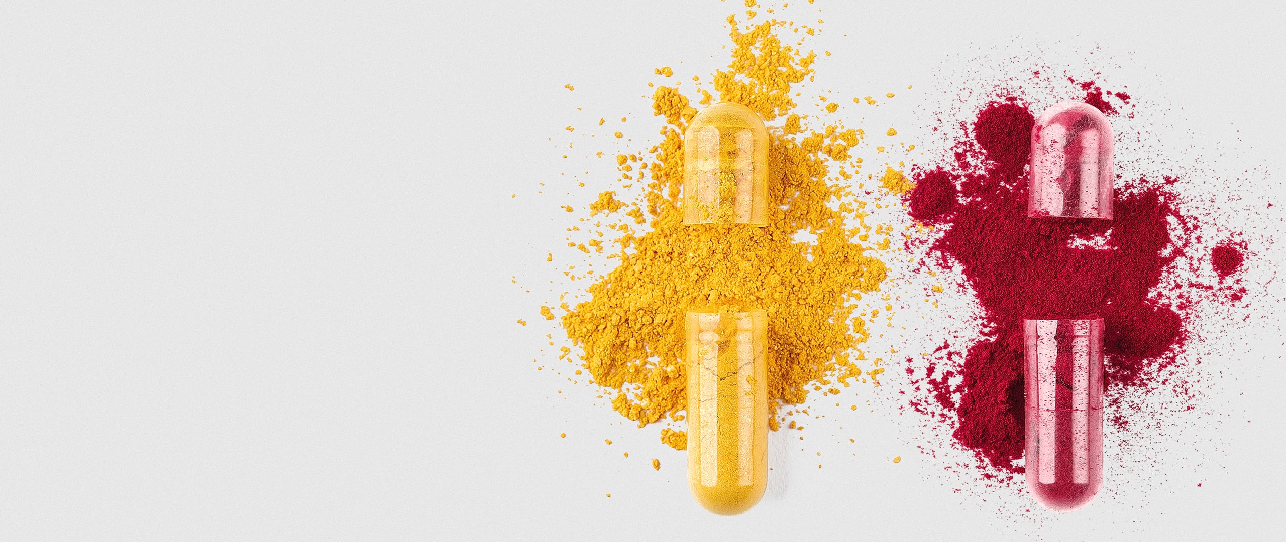 Geöffnete transparente Kapsel, aus der leuchtend gelbes Pulver auf einen hellen Hintergrund rieselt.